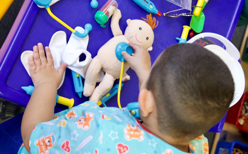 Boy listening to heartbeat using toy stethoscope.