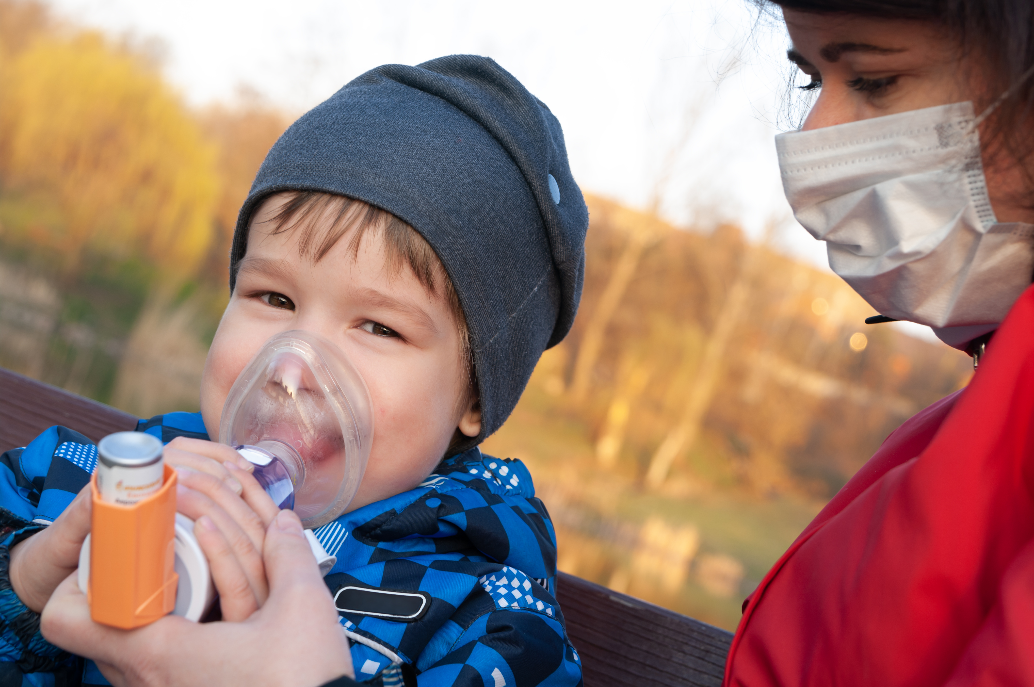 Adulto ayudando a un niño a usar correctamente su inhalador para el asma.