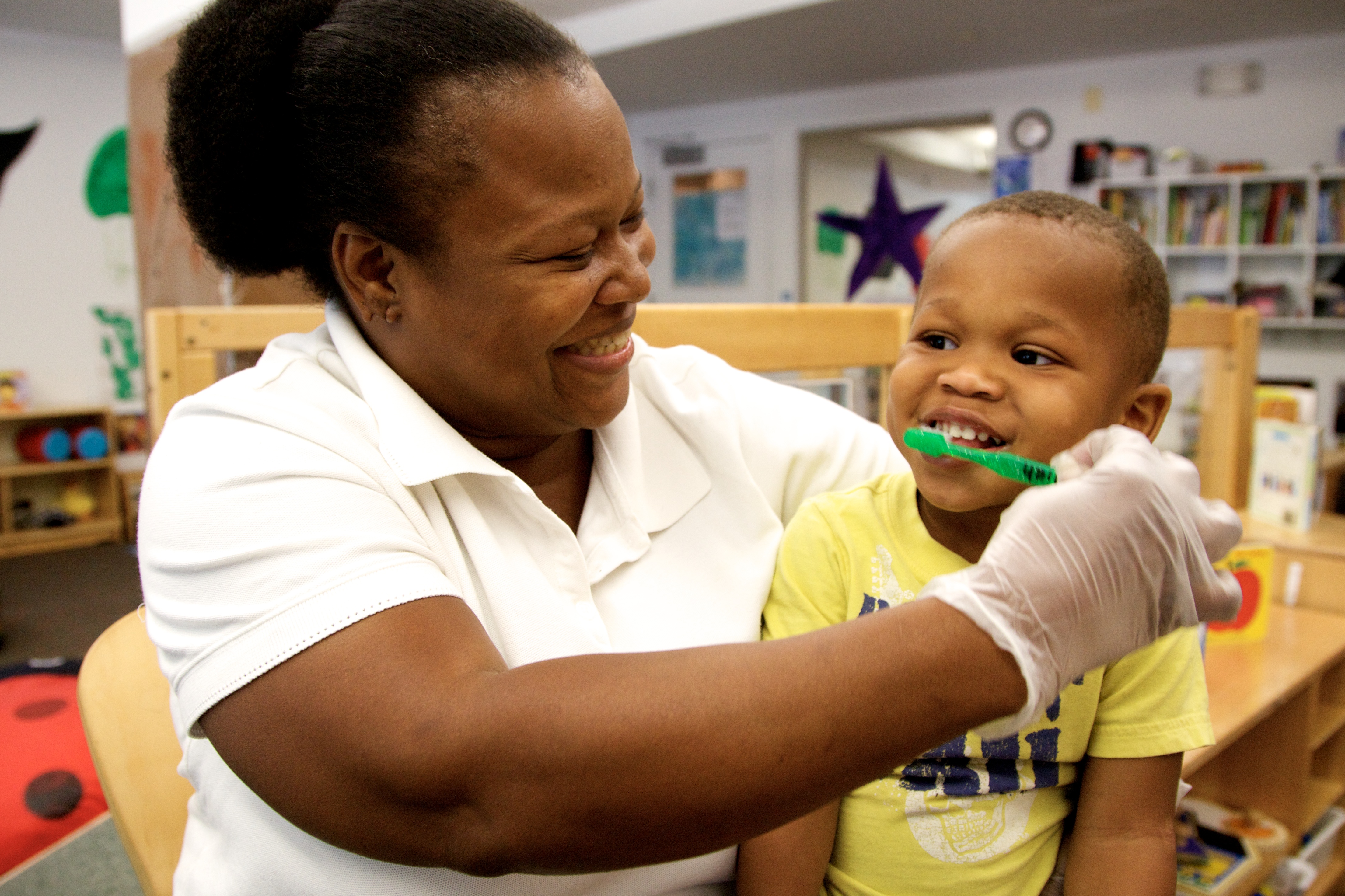 Staff member brushing a young child's teeth.