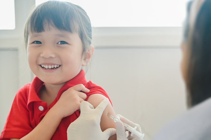 Young child smiling as they get their immunization shot.