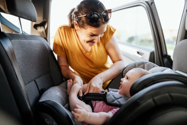 Mujer asegura a un niño en el asiento del automóvil