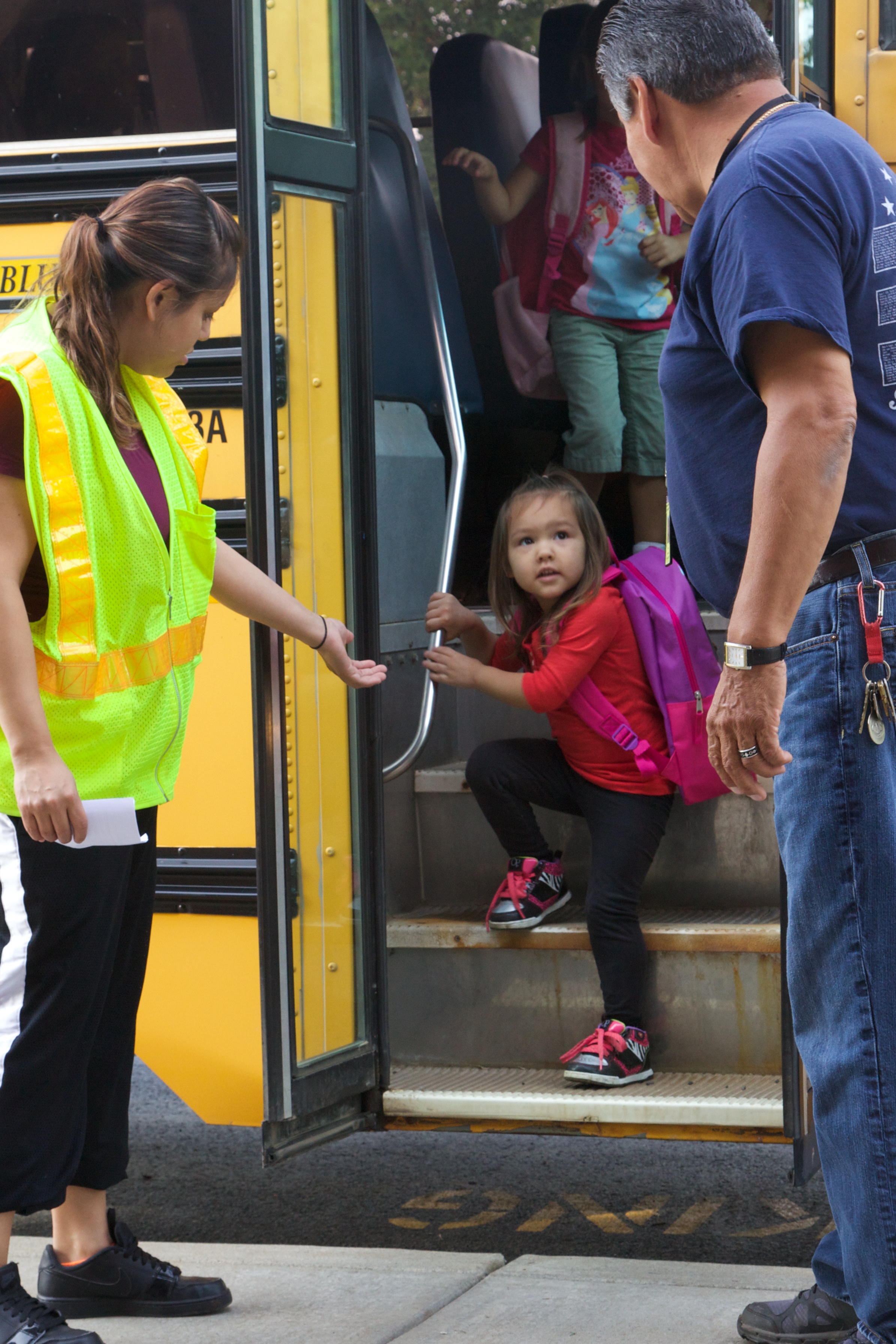 Unos niños suben y bajan del autobús escolar bajo supervisión.