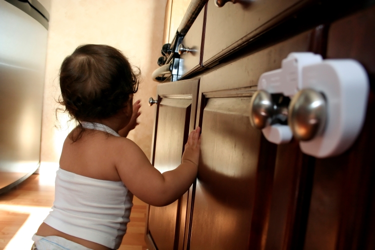 Child walking past kitchen cabinets with child safety locks.