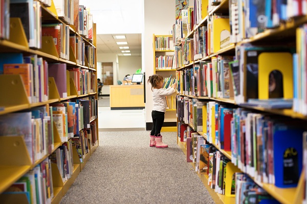 Child looking for a book in a library.