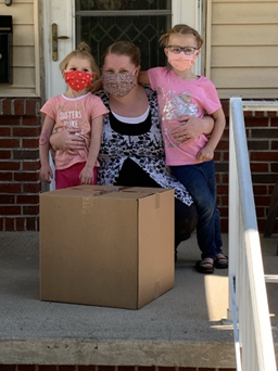 Madre con dos hijos recibiendo una caja.