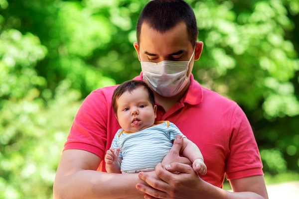 Father using a mask while holding his baby.