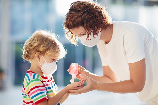 Teacher applying sanitizer to a child's hands.