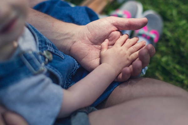 A small child's hand being held by an adult hand.