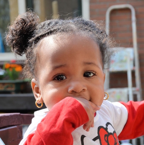 Young girl with hand in mouth while outdoors.