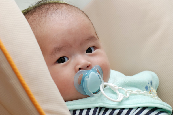 Baby looking sideways with pacifier.