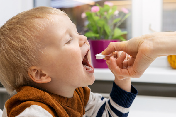 Child being given tablet supplement.