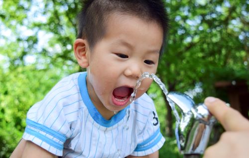 Niño bebiendo de una fuente de agua.