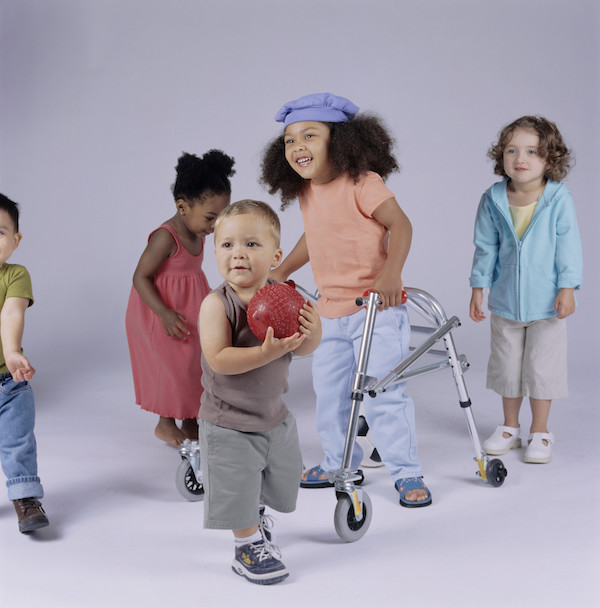 Disabled girl using her walker to play with other children.