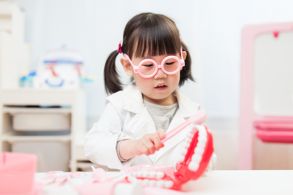 Girl playing with giant toy teeth and gums.