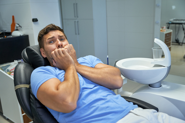 A man clutching his hands together because he is afraid of going to the dentist.