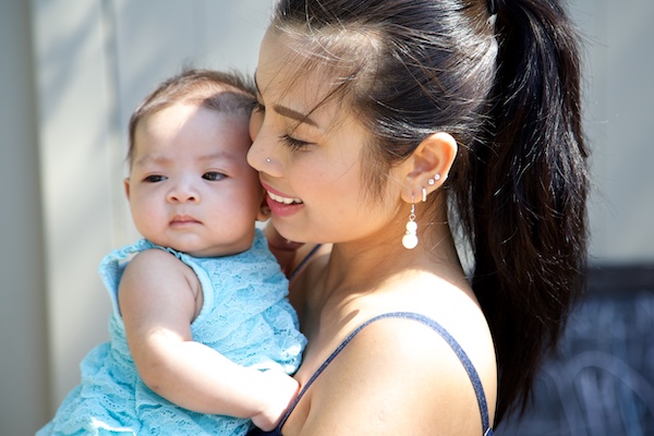 Una madre sosteniendo a su hija pequeña cerca de su mejilla.