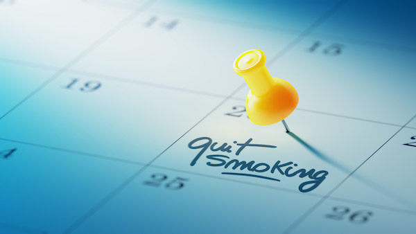 A thumbtack stuck on specific day in a calendar that declares: Quit Smoking.