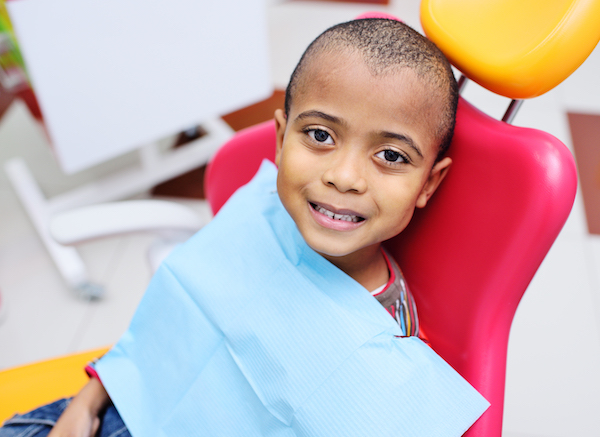 Smiling boy sitting in a red and yellow dentist's chair.