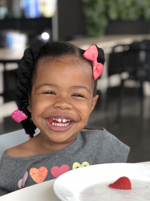 Smiling girl just finished eating a bowl of strawberries, but left one!