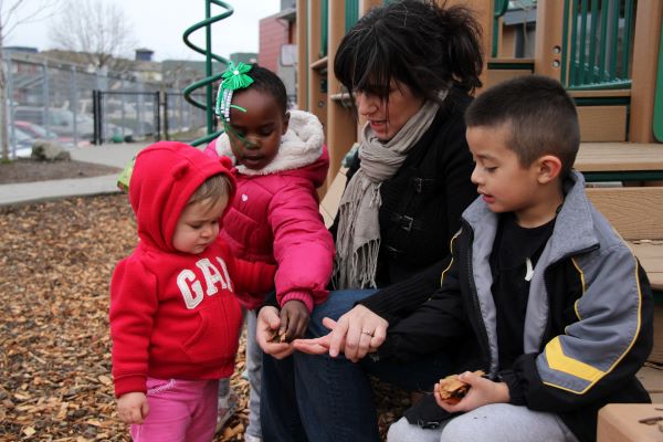 Maestra y niños bien abrigados un día frío en el patio de juego.