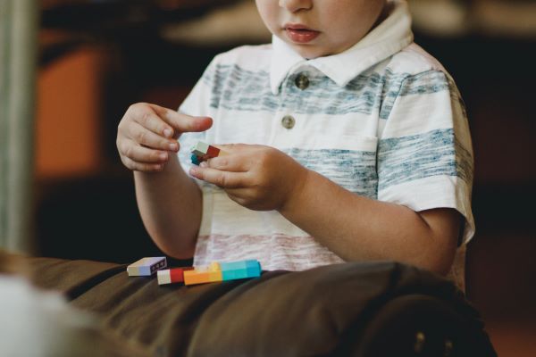 Young boy snapping plastic blocks together.