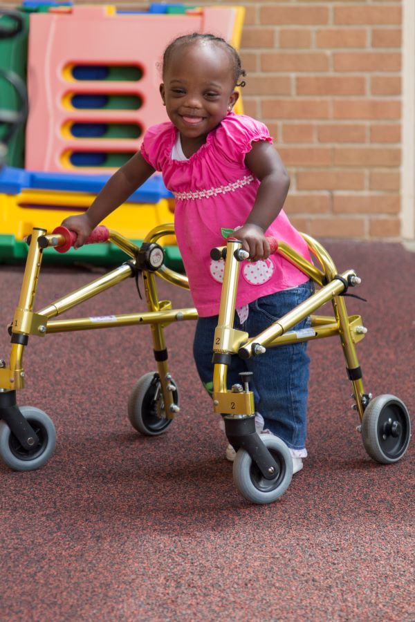 Young girl using a walker in a classroom.