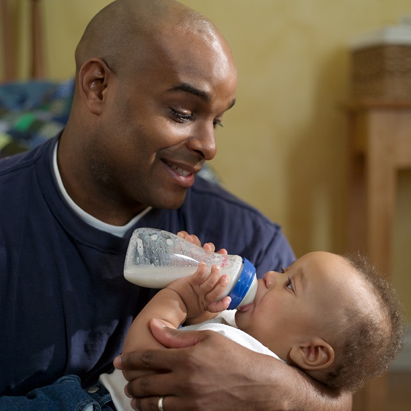 Parent giving his child a bottle of milk