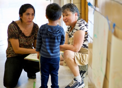 Two women bending down to tend to a child.