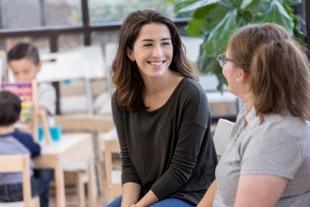 Two smiling women talking with one another.