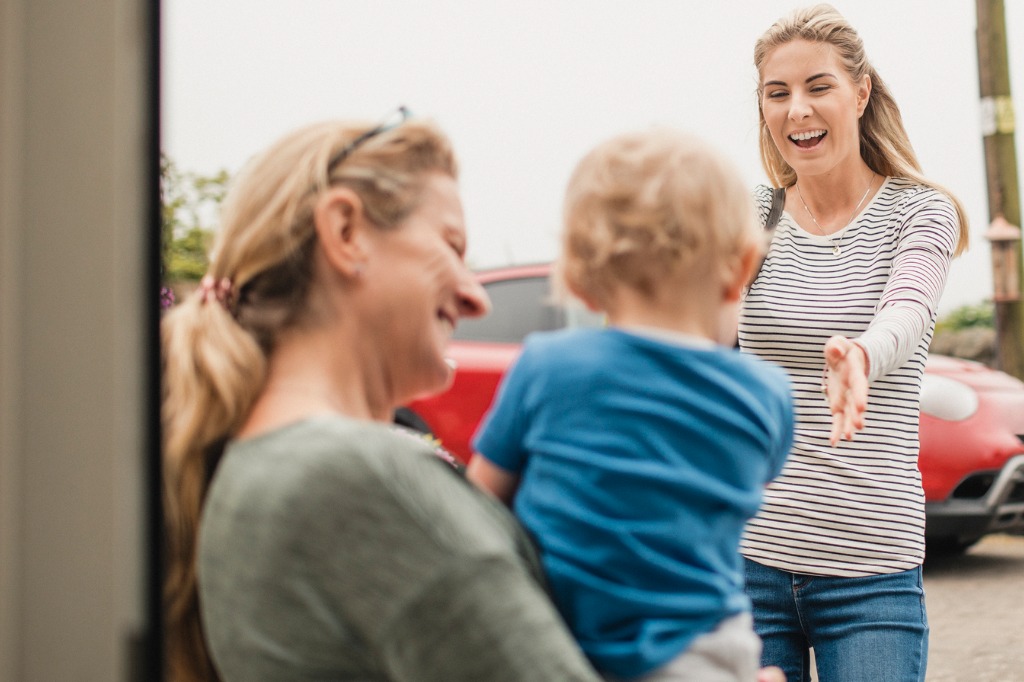 Teacher holding young boy as mother comes to pick him up after work.