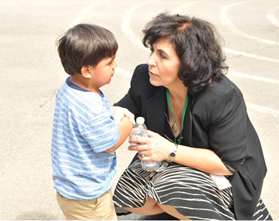 An adult kneeling down to talk to a child who appears to be sad.