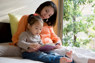 Madre e hija sentadas una al lado de la otra leyendo un libro para niños.