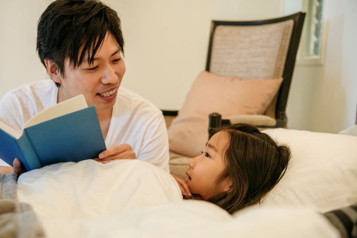 Padre leyéndole un cuento a su hija pequeña antes de dormir.