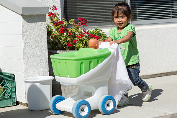 Child pushing a small plastic cart.