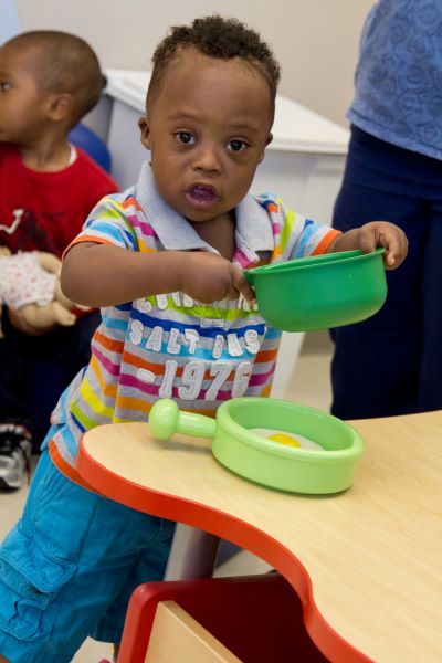 Niño juega con un set de utensilios de cocina de juguete.