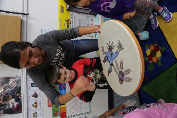 Maestra enseñando a los niños a tocar un tambor.