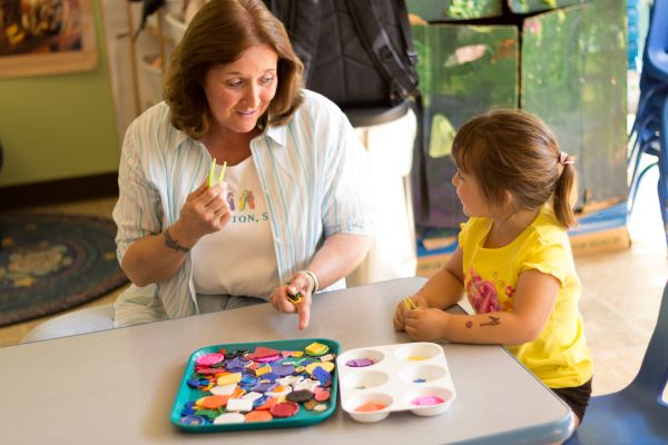 Teacher and child exploring various plastic shapes.