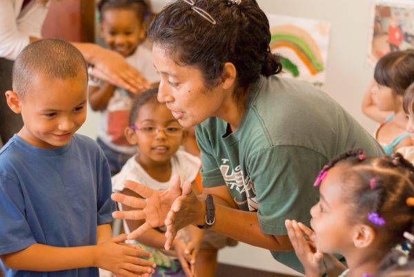 Teacher showing children how to hold their hands and then open them.