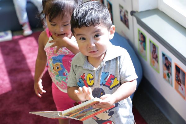 Two smiling children with a book in their hands.