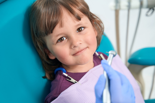 Niño pequeño sentado en la silla del dentista listo para recibir un chequeo dental.