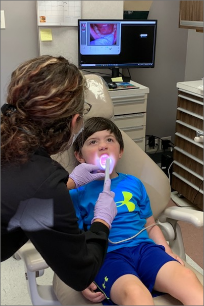 Un técnico dental que examina la boca y los dientes de un niño.