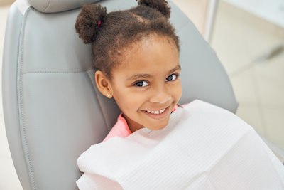 Niña sonriendo en el consultorio de un dentista.