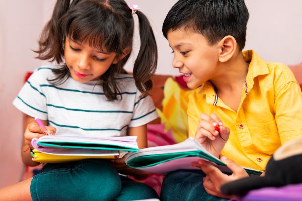 Un niño y una niña escribiendo en sus cuadernos.