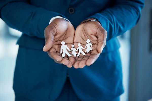 A man's hand cupped together holding paper cutout people.