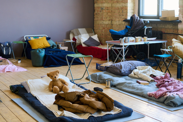 Filas de sacos de dormir en el piso de un gimnasio escolar