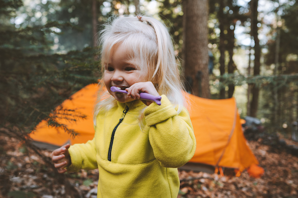 Niña cepillándose los dientes al aire libre