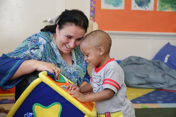 Teacher helping child with a toy.