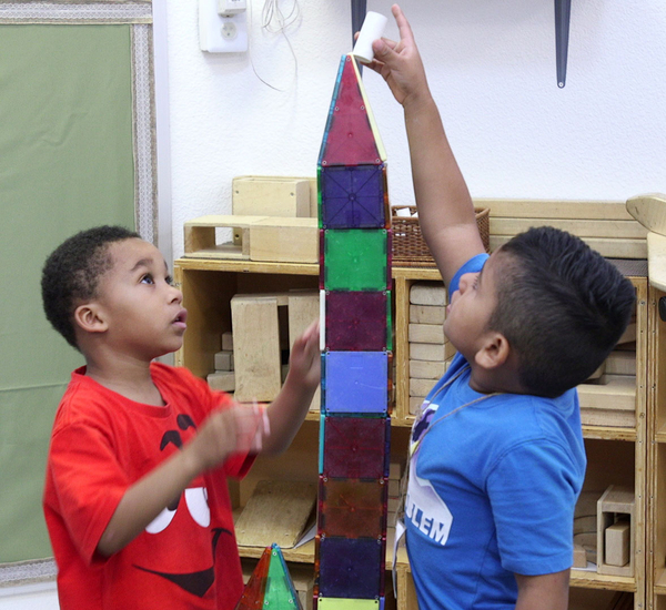 Two young boys creating a tower from blocks.