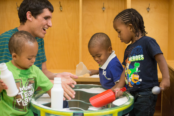 Teacher and three young boys playing with various plastic bottles.