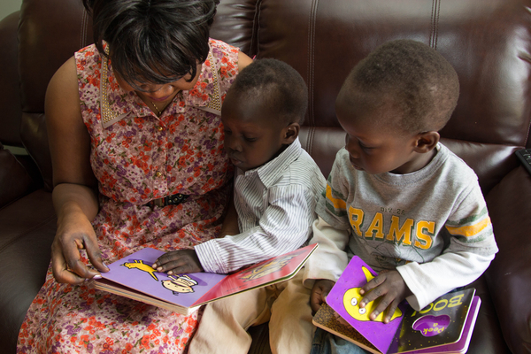 Maestra y dos niños pequeños leyendo juntos